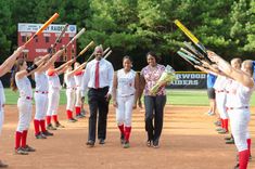 the women's softball team is walking off the field with their bats in hand