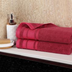 two red towels sitting on top of a white shelf