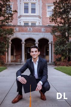 a man kneeling down in front of a building with a graduation cap on his head