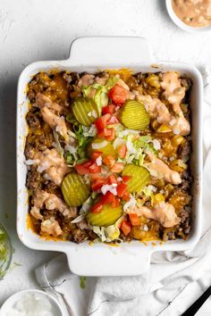 a casserole dish filled with meat, vegetables and sauces on a white table