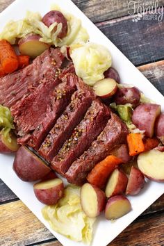 a white plate topped with meat and veggies on top of a wooden table