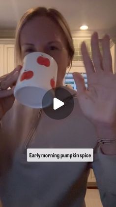 a woman drinking from a coffee cup with her hands in the air