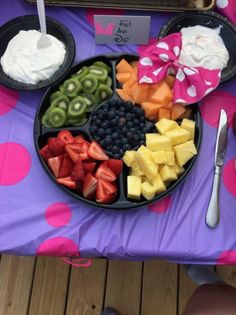 a plate of fruit and yogurt on a purple tablecloth with polka dots