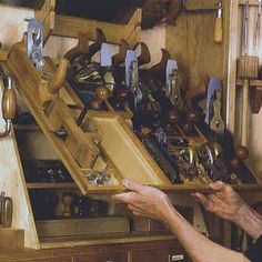 a man is holding a wooden box with many items in it and looking at the drawer