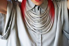 a woman with red hair is wearing a necklace made out of silver wires and leather