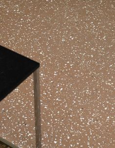 a black table sitting on top of a brown floor next to a white and black chair