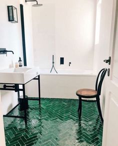 a bathroom with green flooring and a chair next to the bathtub in it