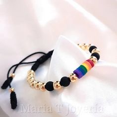 a rainbow bracelet with gold beads and tassels on a white satin bag,