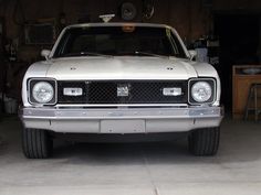 the front end of a silver car parked in a garage