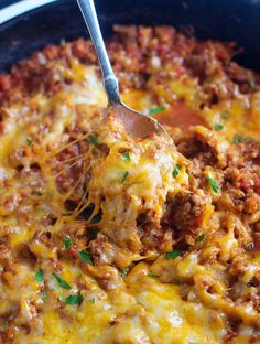 a close up of a spoon in a casserole dish with meat and cheese