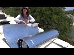 a woman standing on top of a roof next to a large sheet of metal foil