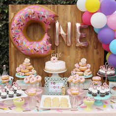 a table topped with lots of cupcakes and donuts next to a balloon