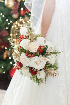 a bridal holding a white and red bouquet in front of a christmas tree