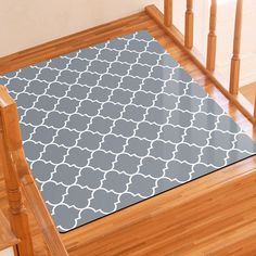 a gray and white area rug sitting on top of a wooden stair case next to a banister