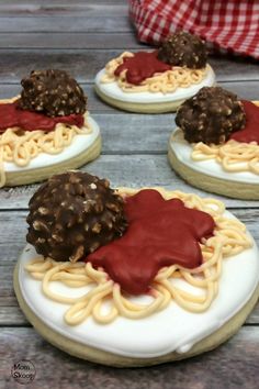 four cookies with different toppings on them sitting on top of a wooden table next to a red and white checkered cloth