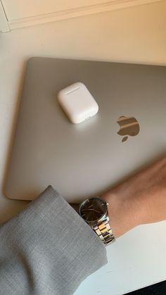 an apple laptop computer sitting on top of a white table next to a person's hand