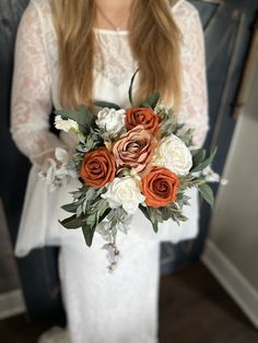 a woman holding a bouquet of flowers in her hands and wearing a white wedding dress