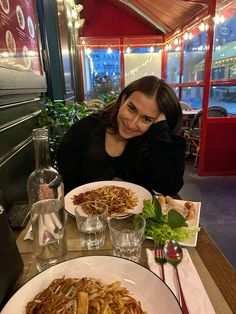 a woman sitting at a table with plates of food