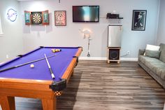 a living room with a pool table, couch and flat screen tv on the wall