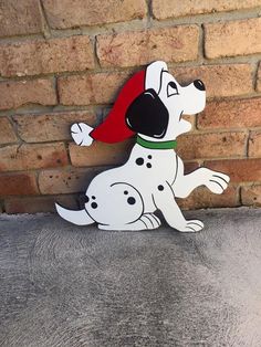 a wooden dog with a red hat on it's head sitting against a brick wall