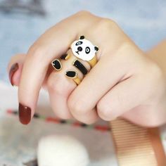 a woman's hand with a panda bear ring on top of her finger,