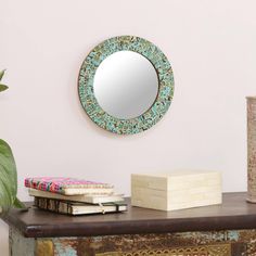 a mirror sitting on top of a wooden table next to a vase and planter