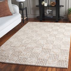 a living room area with a white couch and wooden flooring, along with a rug on the floor