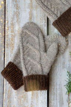 two mittens sitting on top of a wooden table next to a potted plant