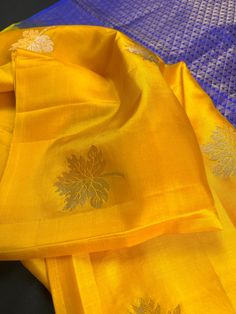 SILK MARK CERTIFIED !!! Gorgeous Borderless Mango Yellow Saree with contrast Pallu and Blouse Piece in Blue Color. The Saree has Leaves Motifs with half of the leaf in Sliver and another half weaved in Gold Zari. The pallu is weaved in Gold Zari. Beautiful combination and a unique Saree. Item : SareeBase Fabric : Pure Kanjivaram Soft Silk Color : Mango Yellow and Blue Blouse piece : Comes with un-stitched Blouse piece.Blouse material : Pure Kanjivaram Soft Silk Work : HandloomFall & Edging(Yes/N Embroidered Slub Silk Traditional Wear For Celebration, Celebration Embroidered Slub Silk Traditional Wear, Yellow Anarkali Blouse With Motifs, Yellow Zari Work Blouse For Celebration, Yellow Blouse Piece With Zari Work For Celebrations, Wedding Blouse Piece With Motifs In Slub Silk, Yellow Blouse Piece For Celebration Festivals, Yellow Blouse Piece For Festivals And Celebrations, Yellow Blouse For Celebration And Festivals