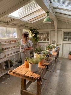 a woman standing in a room filled with potted plants