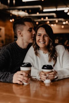 a man and woman sitting at a table holding coffee cups