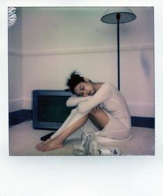 a woman sitting on the floor next to a tv with her arms around her head