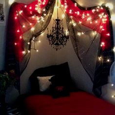 a bed with red sheets and lights on the headboard