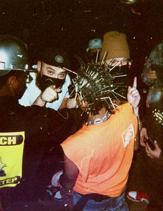 a group of people standing around each other with helmets on and pointing at something in the air