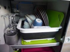 the dish rack is full of dishes and utensils in this small kitchen cabinet