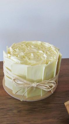 a cake with white frosting on top of a wooden table next to a knife