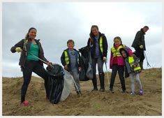 a group of people standing on top of a sandy beach next to bags and shovels