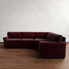 a red couch sitting on top of a hard wood floor next to a white wall