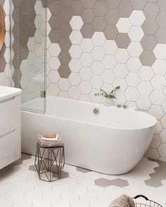 a bathroom with hexagonal tiles on the wall and floor, including a bathtub