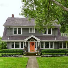 a gray house with red front door and white trim on the windows is featured in this magazine