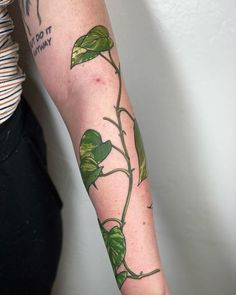 a woman with a tattoo on her arm has a green plant growing out of it