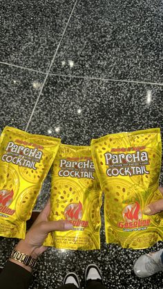 two bags of paracha cocktail sitting on top of a counter next to someone's feet