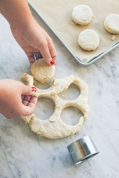 a person is making homemade cookies on a table with cookie cutters and baking sheet