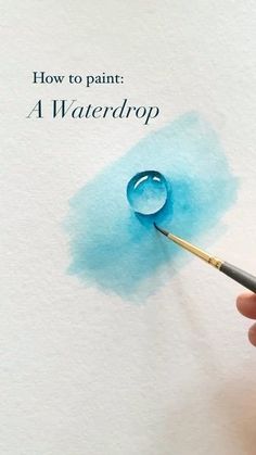 a hand holding a paintbrush and painting the bottom of a piece of paper with watercolor on it