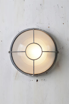 a light that is on the side of a wall with a circular glass shade over it