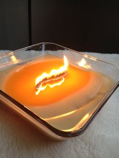 a lit candle in a glass dish on a white blanket