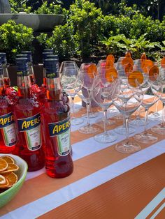 there are many bottles and glasses on the table with orange slices in front of them