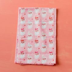 a pink napkin with white llamas and santa hats on it, against a coral colored background