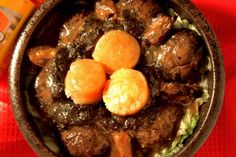 a bowl filled with meat and veggies next to a bottle of orange juice