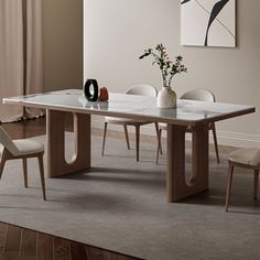 a dining table with two chairs and a vase on the table in front of it